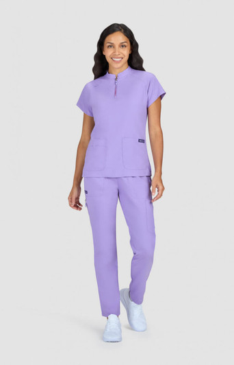 A medical uniform set in lavender featuring a short-sleeved top with a zip and matching trousers. It includes a logo.