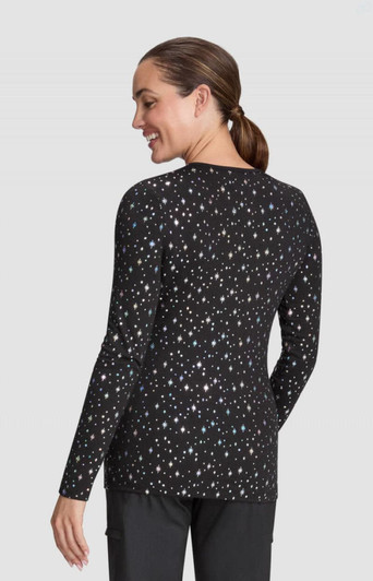 A woman models a black long-sleeve Tessa Tee featuring a scattered print of colourful dots. The tee has a fitted silhouette.