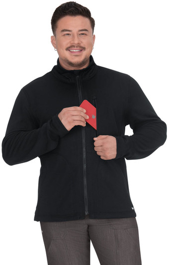 A man wears a black jacket with a zippered front, holding a red item in his hand. The jacket features a logo.