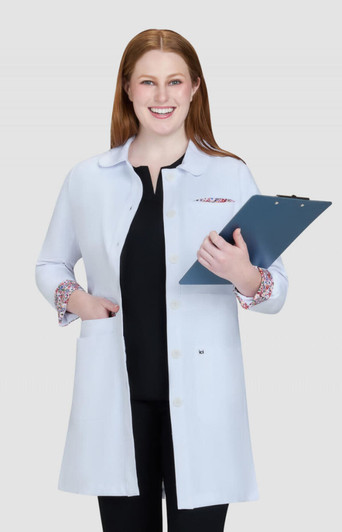 A lab coat in light blue with patterned cuffs, held by a smiling woman, with a clipboard in her hands.