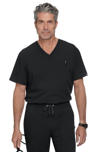 A man in a black V-neck scrub top stands confidently, wearing black trousers and holding glasses. The outfit features a pocket and branding.