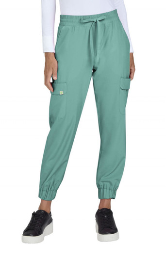 A pair of teal jogger pants featuring cargo pockets and elastic cuffs, worn with black shoes. The model is indoors.