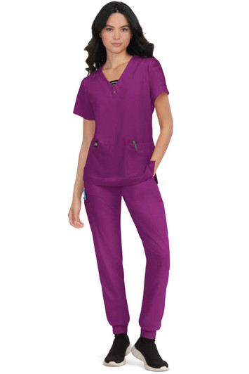 A scrub outfit in vibrant purple featuring a top with pockets and matching pants, complemented by a logo.