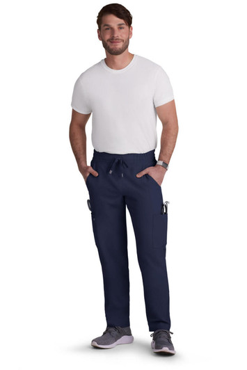 A man in navy neuro cargo pants with pockets, paired with a white T-shirt and grey shoes. The pants have a branding logo.