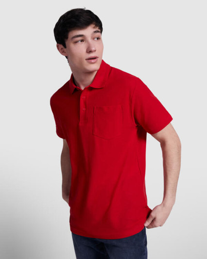 A red polo shirt featuring a collar and a chest pocket, modelled by a young man with a neutral background.