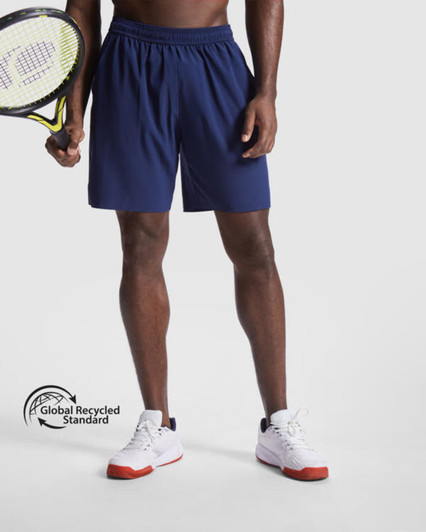 Navy sports shorts with an elastic waistband, held by a person holding a tennis racket. Features a logo.