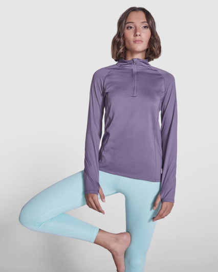 A purple women's sweatshirt with a half-zip design, paired with light blue leggings, features a logo on the chest.