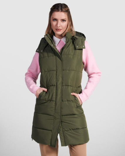 A women's padded vest in olive green, featuring a hood and side pockets, worn over a pink top.