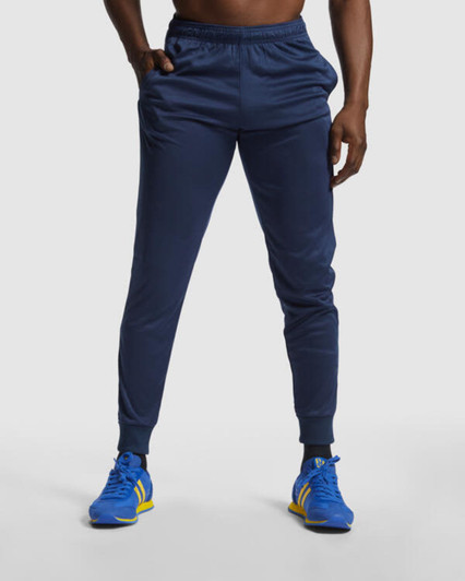 Navy track pants with a fitted design, featuring an elastic waistband and cuffs. The model wears sporty shoes.