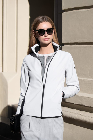 A women's jacket in white with black accents, featuring a zip-up front and a high collar. The model wears sunglasses.