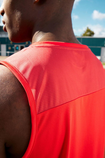 A men's running tank in bold red, featuring a mesh back and a logo. The fabric appears lightweight and breathable.