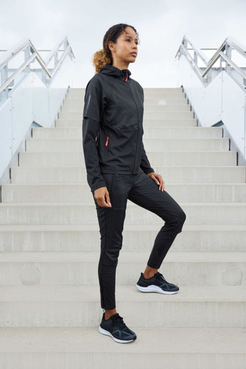 A black ladies running jacket features a hood and zippered pockets, paired with black athletic pants and shoes.