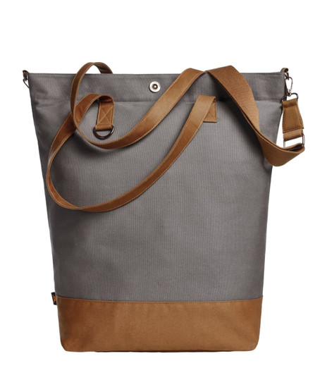 A grey tote bag with a brown leather base and adjustable strap, featuring a logo.