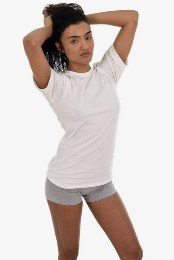 A short sleeve fine jersey crew tee in white, worn by a model posing with one hand in her hair.