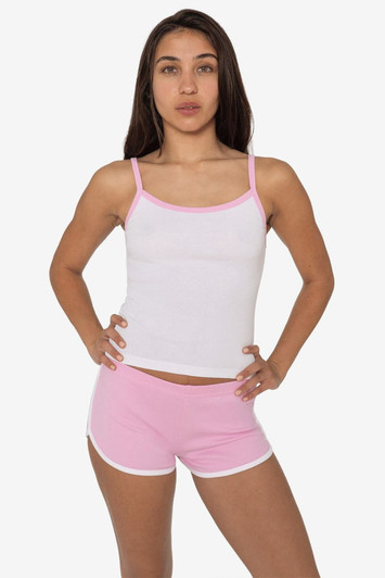 A model wearing a white spaghetti tank top with pink accents, paired with pink shorts, featuring a logo.