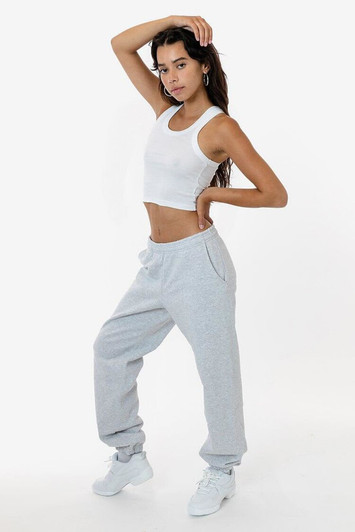 A model poses in grey heavy fleece sweatpants, paired with a cropped white tank top and white sneakers.
