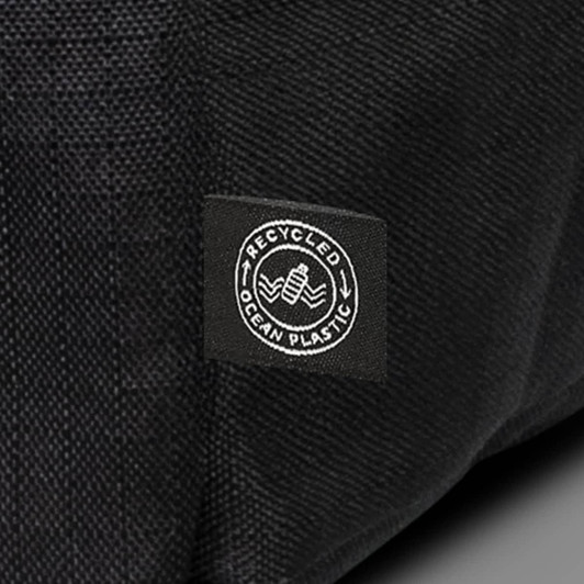 A black backpack made from recycled ocean plastic with a small logo patch.
