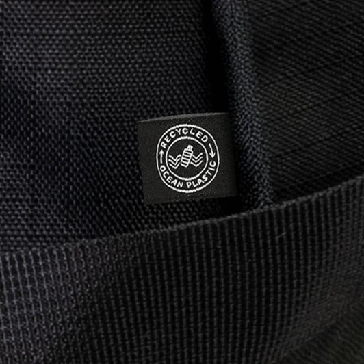 A black duffle bag made from recycled ocean plastic, featuring a small logo tag.