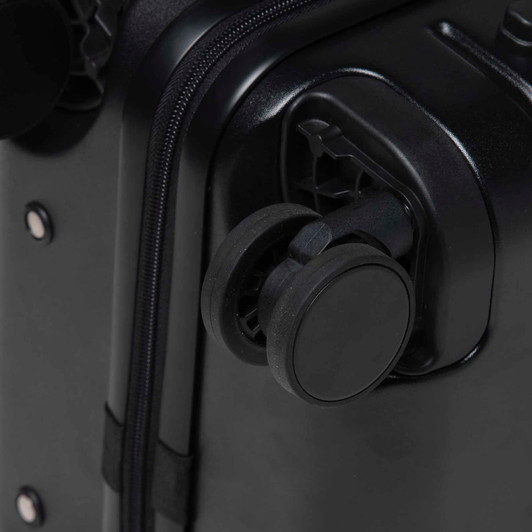 A close-up of a black hardcase trolley with a wheel and zipper detail. The product features a logo.
