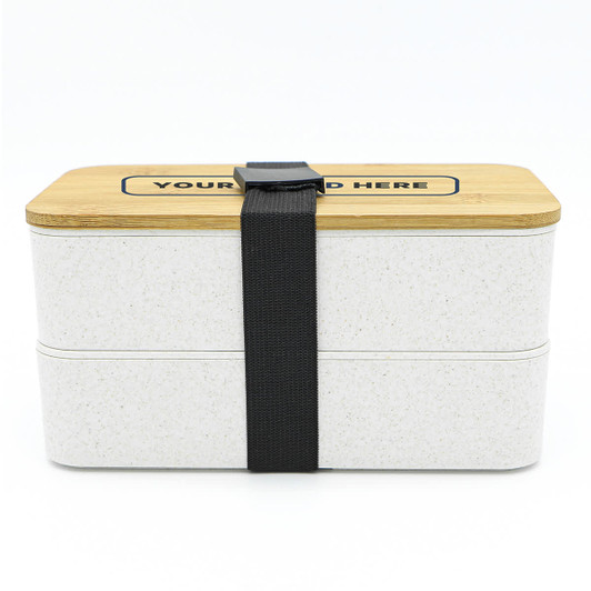 A two-layer lunch box in white with a bamboo lid, secured by a black strap. It features a logo on the top.