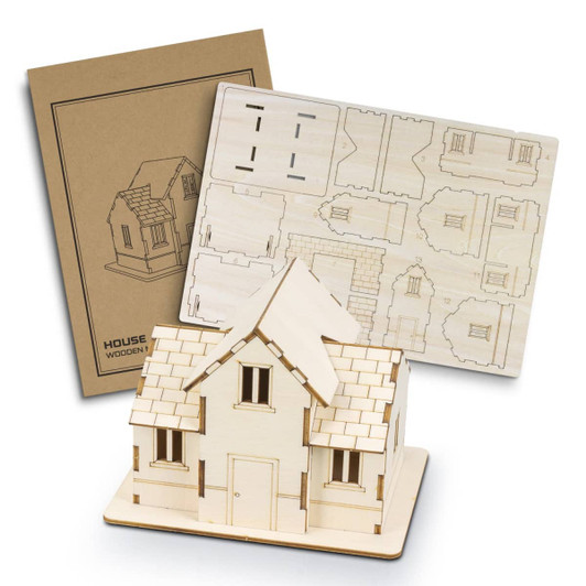 A wooden model of a house in natural wood colour, displayed with a laser-cut assembly sheet and a packaging design.