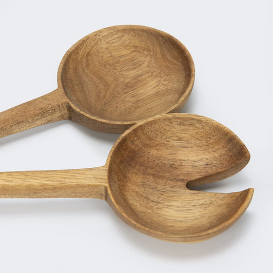 Two wooden salad servers in natural brown hues, featuring a spoon and a fork design, resting on a light background.