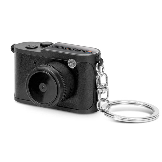 A small black camera keychain with a detailed lens and a keyring attachment. It has a logo on the top.
