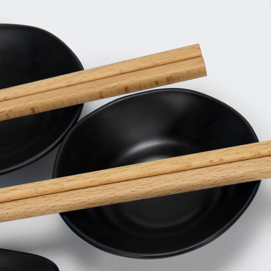 A set of black bowls accompanied by wooden chopsticks, featuring a simple and elegant design.