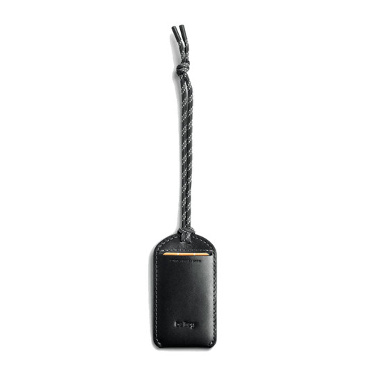 A black leather luggage tag features a braided strap and a logo. The design is sleek and minimalist.