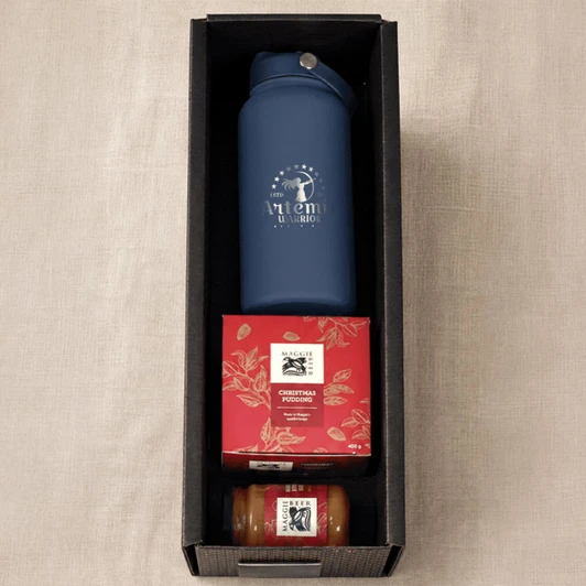 A blue drink bottle, a Christmas pudding, and a jar of sauce in a black box hamper.