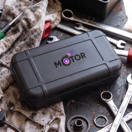 A black tool case with a logo, resting on a work surface surrounded by wrenches and a dirty cloth.