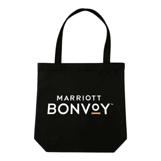 A black tote bag with handles, featuring a logo on the front, placed on a wooden table.
