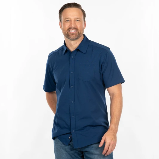A short sleeve shirt in navy blue with a button-down front and a chest pocket, worn by a smiling man.