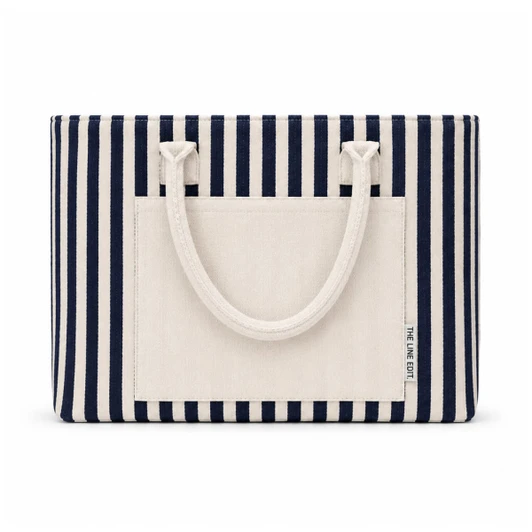 A striped tote bag featuring navy and cream colours, with a flat pocket and sturdy handles. It has a logo.
