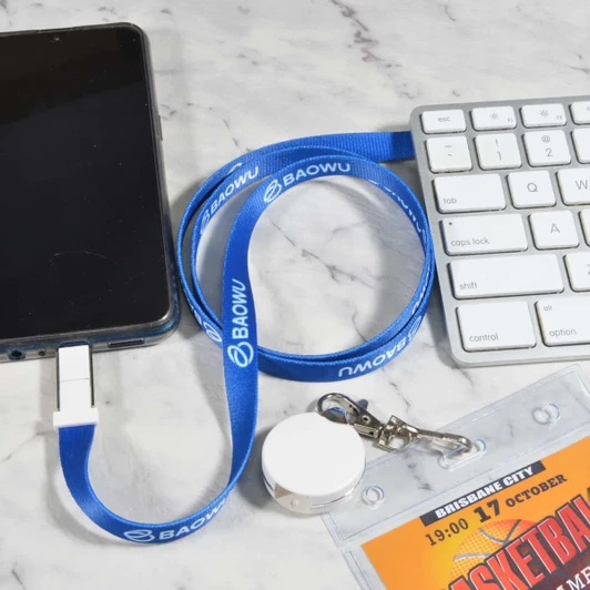 A blue lanyard cable with a USB connector rests next to a smartphone and keyboard on a marble surface.