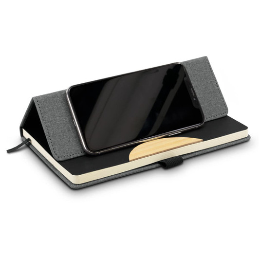 A grey notebook with a phone resting on its cover, featuring a smooth surface and a decorative design.