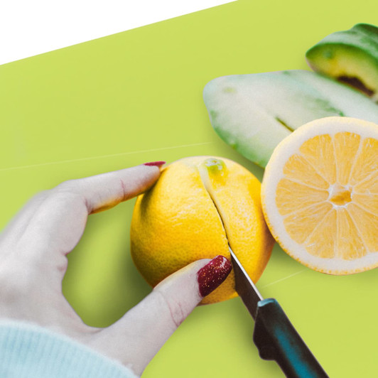 A bright green foldable chopping board with a hand cutting a lemon on it, featuring a sliced lemon beside it.