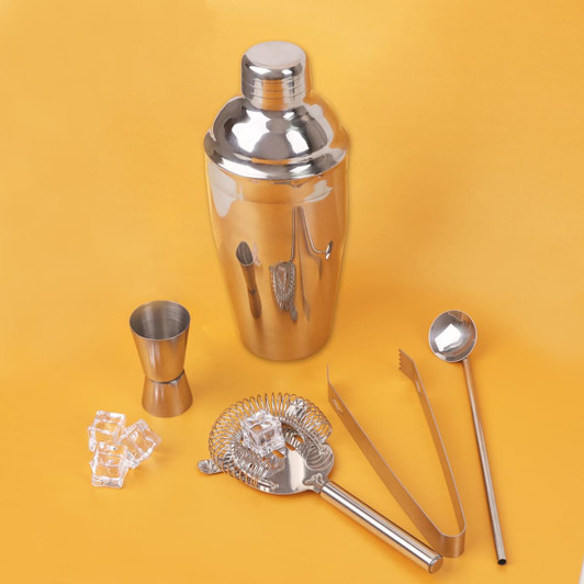 A drink bottle with a shiny stainless steel shaker, strainer, jigger, tongs, and stirring spoon, all in silver.