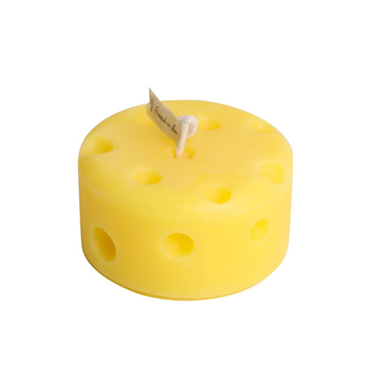 A round yellow candle designed to resemble cheese, featuring holes and a wick at the top.