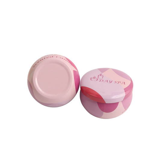 Two pink tin candles with a decorative design, featuring a logo on the lid.