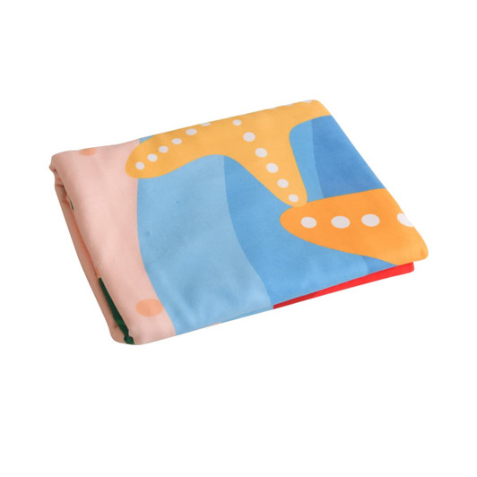 A folded microfibre beach towel featuring a colourful abstract design in blue, yellow, and pink, with a logo.