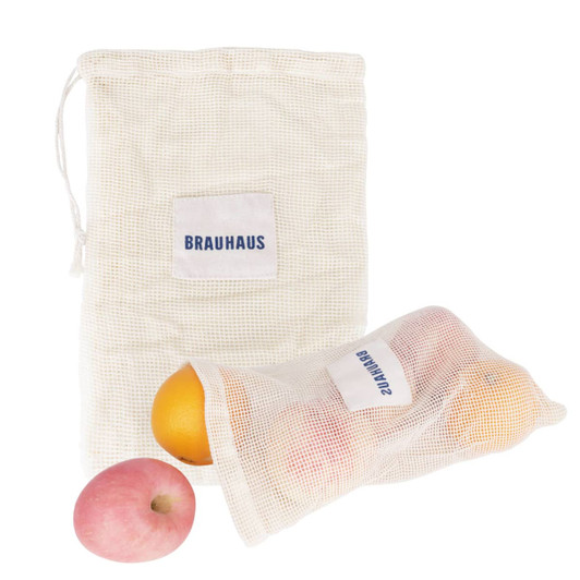 A cream-coloured organic cotton mesh bag with a drawstring, containing oranges and an apple. It features a logo.