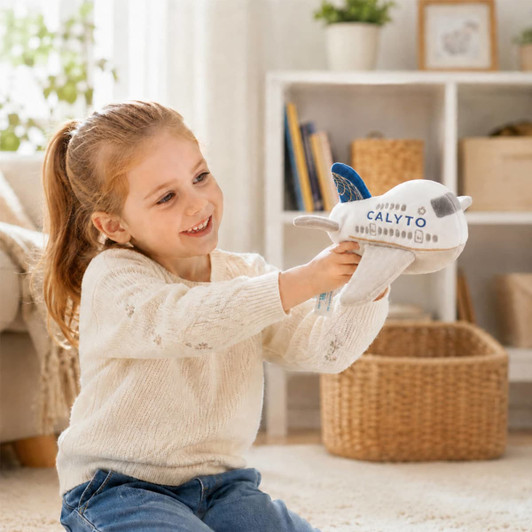 A child smiles while holding a plush airplane toy in white and blue, featuring a logo. The scene is bright and cheerful.