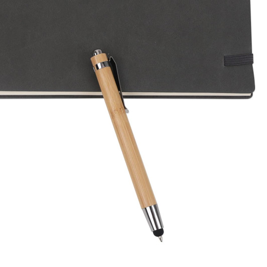 A bamboo pen with a stylus nib rests on a dark notebook, featuring a metal clip and shiny accents.