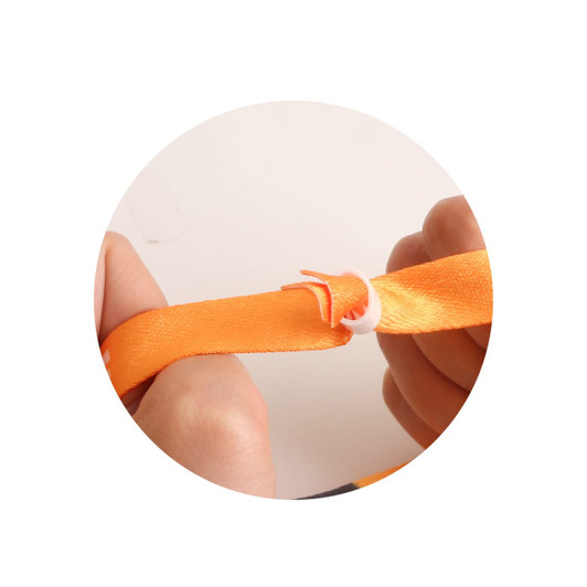 An orange RPET fabric wristband being secured with a plastic connector, held in hands.