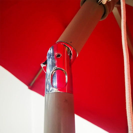 A close-up view of a chrome mechanism on a red commercial market umbrella, featuring a sturdy pole and attachment details.