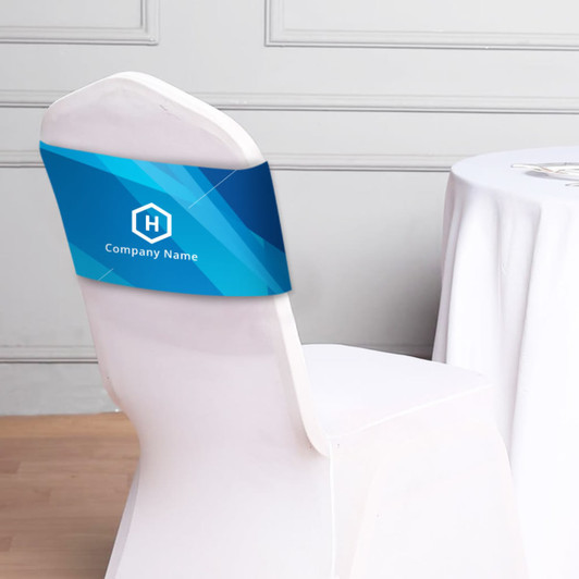 A blue chair band featuring a logo, displayed on a white chair beside a table covered with a cloth.