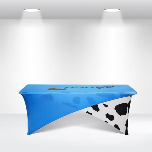 A blue and white stretch table cloth with a cow print design, fitting a 6ft table and featuring a logo.
