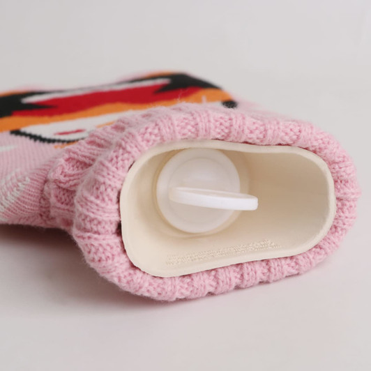 A pink hot water bottle with a knitted cover, featuring a cute design and a plastic opening at the top.