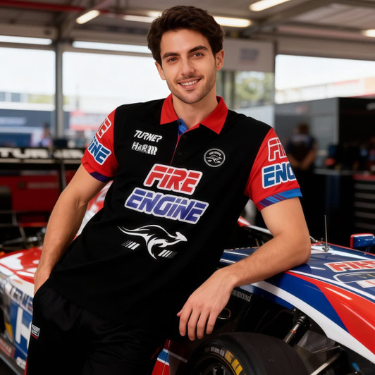 A man wearing a black polo shirt with red and blue sleeves, featuring a logo and branding, leans against a race car.